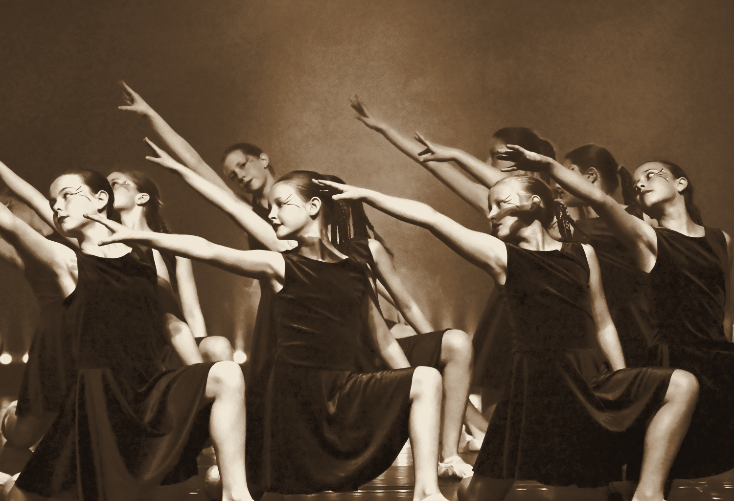 Groupe de danseuses en robe bordeaux, bras tendus lors du spectacle